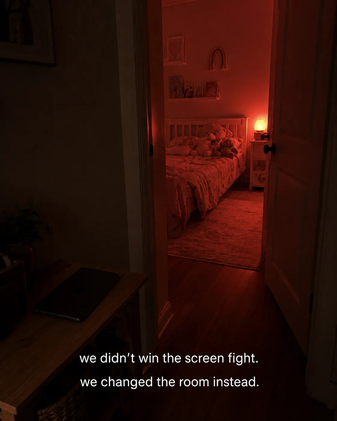 A child's bedroom in soft red night mode, tablet left outside the door